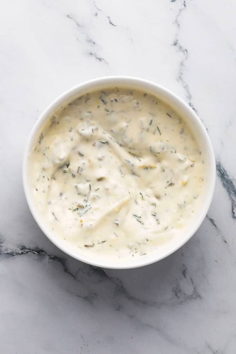 Close-up of homemade tartar sauce with cornichons and herbs.